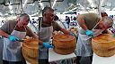 Taliansky syrár rozkrajuje bochník syra „parmigiano reggiano“