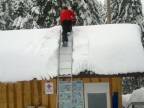 Slovinský záchranár odpratáva zo strechy sneh