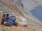 Štyria chlapi sa snažia nohami uvoľniť na brehu jazera veľký balvan (Turecko)
