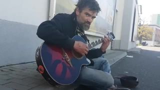 Bezdomovec Tomáš hrá na gitare pri bratislavskom markete (2017)