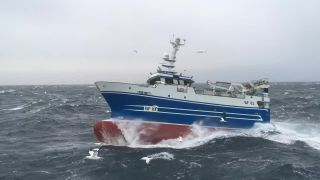 Rybárska loď v bojuje s masívnymi vlnami na rozbúrenom mori