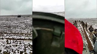 Ukrajinskí vojaci postupujú na snehu v rade za obrneným vozidlom