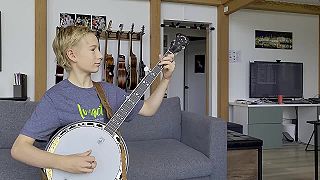 Malý blonďavý talentovaný hráč na bendžo